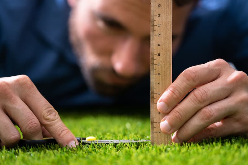 Ein Mann misst beim Schneiden von Gras, was ist Perfektionismus?